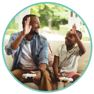 Father and son sharing a high five on the couch while playing video games