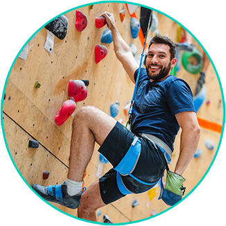 Smiling man climbing a red indoor rock wall